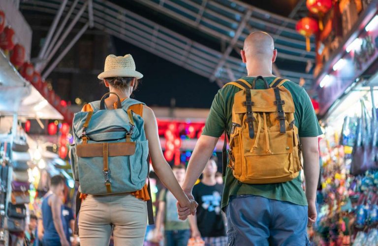 How Digital Communication Enhances Travel Blogging, woman and men from the back, travelling around the world with backpacks